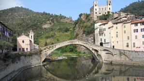 A stone bridge over a calm river, with buildings and a castle on a hillside in the background. - Solaria 1 and 2 - Ospedaletti Ligure - Lungomare C Colombo Nrfloor (Ospedaletti)
