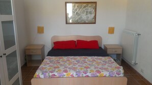 A bedroom with a bed, two bedside tables, a nightstand, a radiator, and a wall-mounted artwork. - Studio Apartment in Countryside Villa With Swimming Pool (Ragusa)