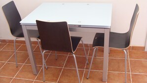 A small dining area with a white table and two black chairs with metal legs. - Studio Apartment in Countryside Villa With Swimming Pool (Ragusa)