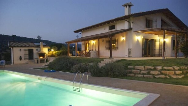 A two-story house with a swimming pool, outdoor seating, and a stone wall. - Studio Apartment in Countryside Villa With Swimming Pool (Ragusa)
