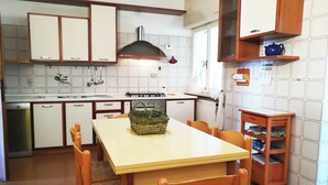 A kitchen with a dining table, chairs, a basket, and a small cabinet. - Villa Lina for 7 Persons Near the Beach (Fondi)