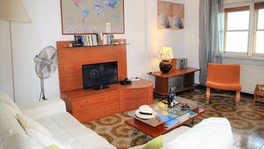 A living room with a television, a map on the wall, a fan, a lamp, and a chair. - Villa Lina for 7 Persons Near the Beach (Fondi)