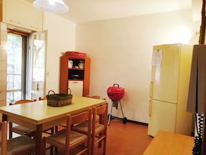 Une cuisine compacte comprenant une table à manger, des chaises, un réfrigérateur, un four à micro-ondes, un panier et une petite étagère.