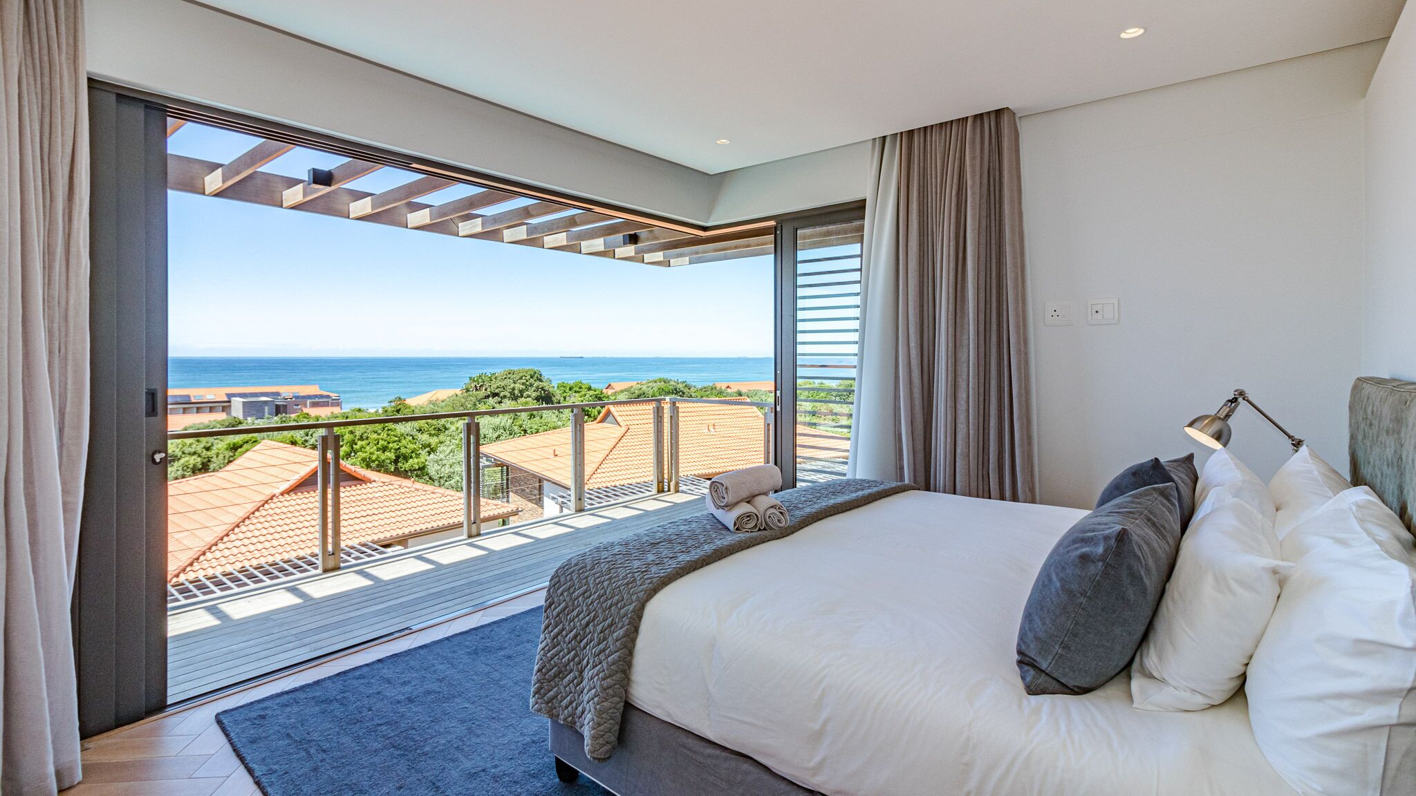 A bedroom with a large bed, a view of the sea, and a balcony.