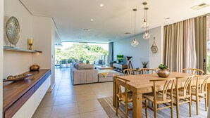 A modern living room with a sofa, coffee table, and dining table with chairs. There is a TV and a plant on the table. - Zimbali by Euphoric, Zimbali Coastal Resort, Ballito (Ballito)