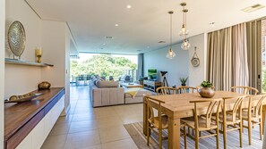 Un salon moderne avec un canapé, une table basse et une table à manger avec des chaises. On y trouve également un téléviseur et une plante posée sur la table.