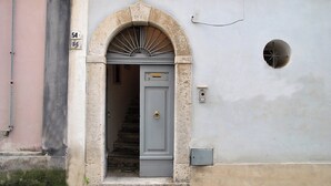 A building entrance with a stone archway, a grey door, and a small circular window on the wall. - Belvedere Home With sea View on the Gulf of Gaeta (Gaeta)