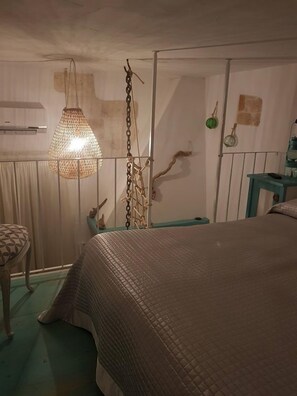 Un dormitorio con cama, lámpara colgante, armario y una silla.