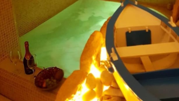 Une pièce avec un sol carrelé, un petit bateau, une bouteille et un bol.