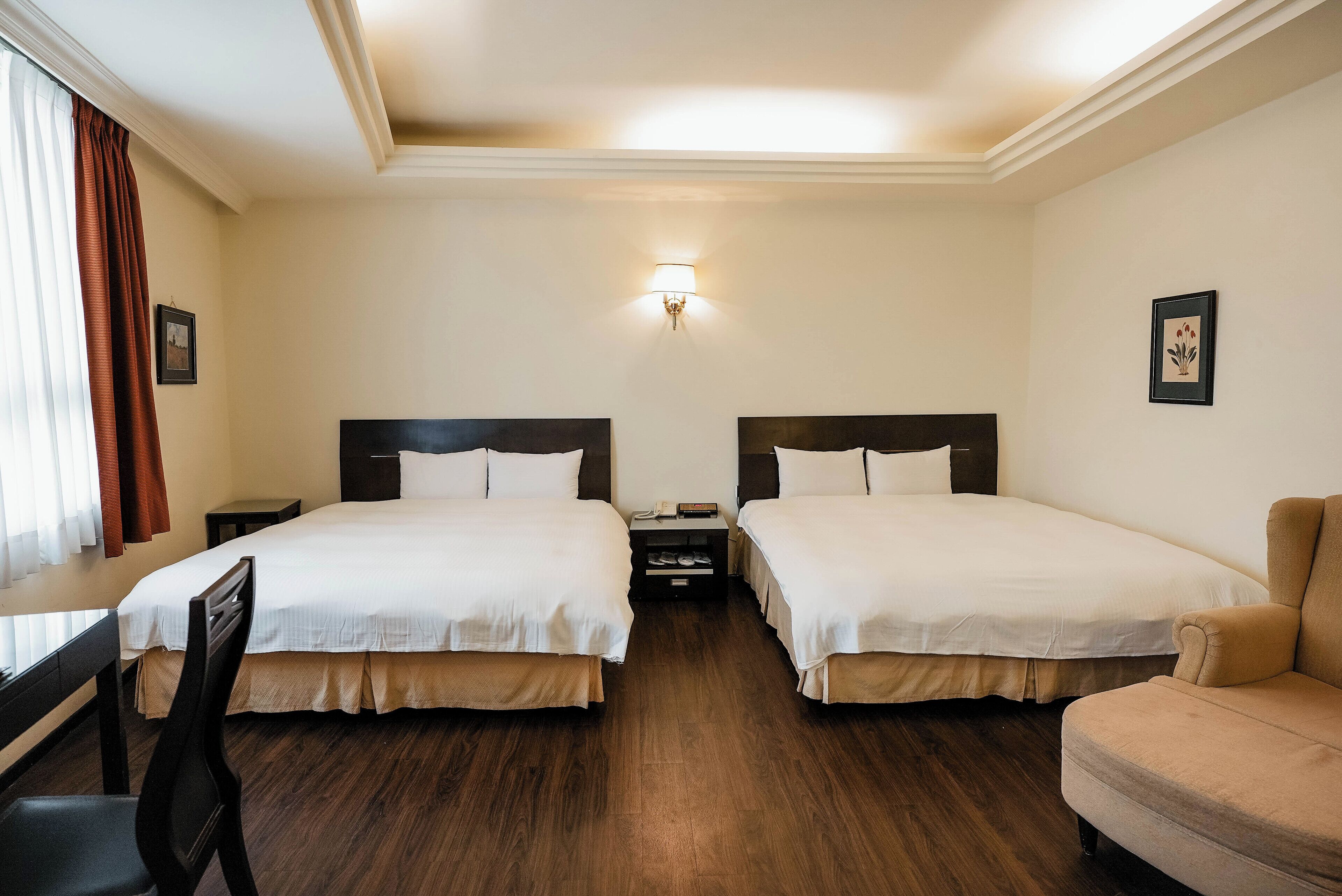 A hotel room with two beds, a desk, a chair, and a sofa.