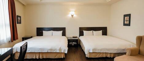 A hotel room with two beds, a desk, a chair, and a sofa.