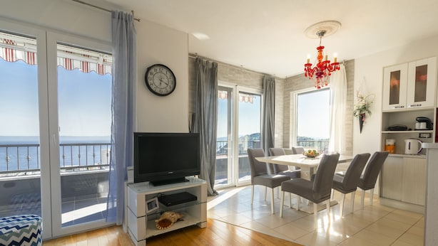A modern living room with a television, dining area, and a balcony with a view. - La Storia Apartments (Makarska)