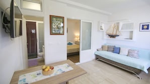 A compact living space with a dining table, a sofa, and a small kitchen area. - La Storia Apartments (Makarska)