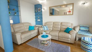 A living room with two beige sofas, a coffee table, and a blue accent wall. - La Storia Apartments (Makarska)