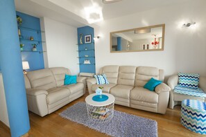 A living room with two beige sofas, a coffee table, and a blue accent wall. - La Storia Apartments (Makarska)
