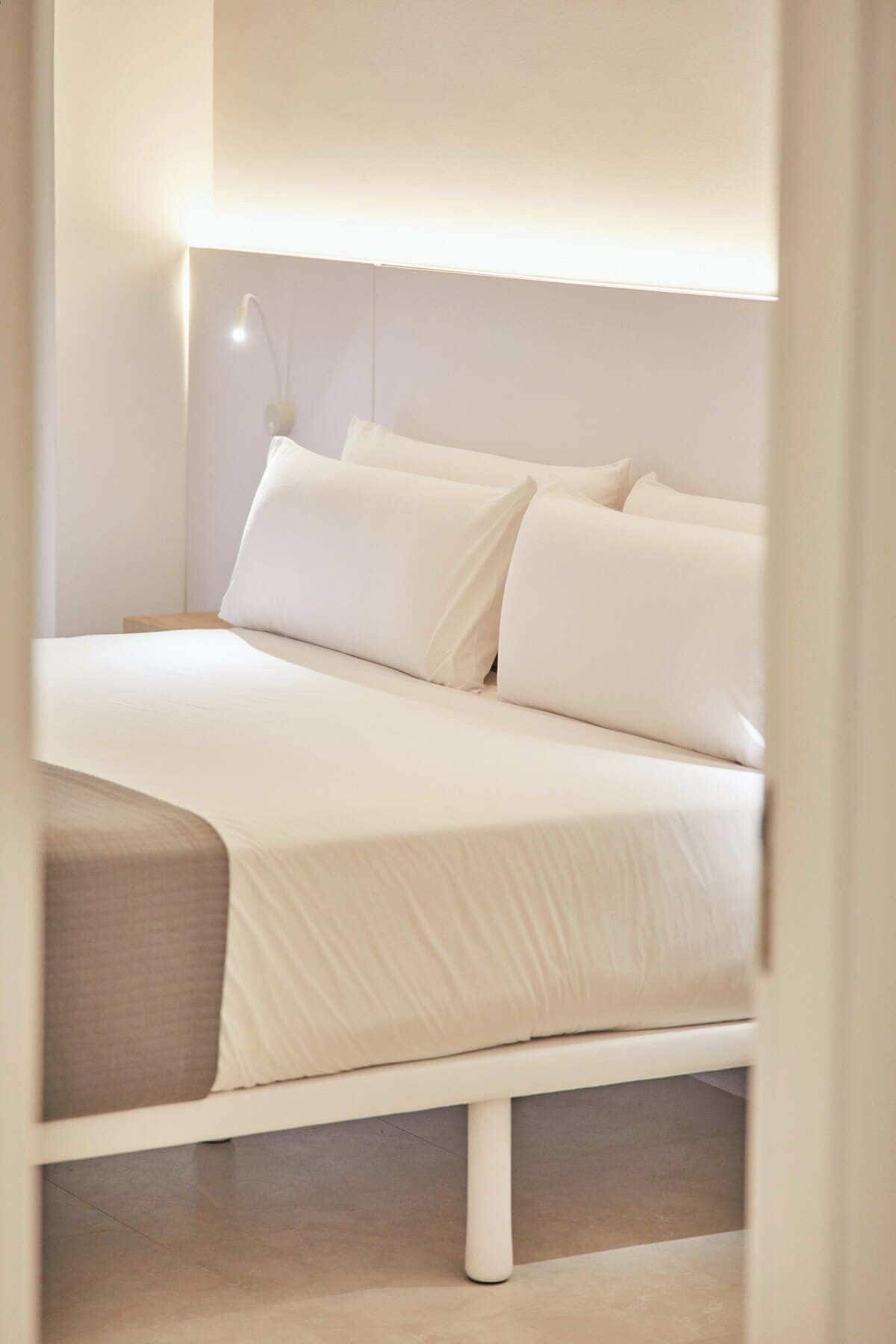 A bed with white bedding and a bedside lamp.