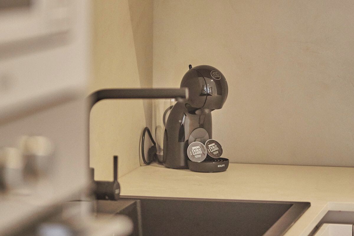 A modern kitchen with a built-in coffee machine and a single cup holder.