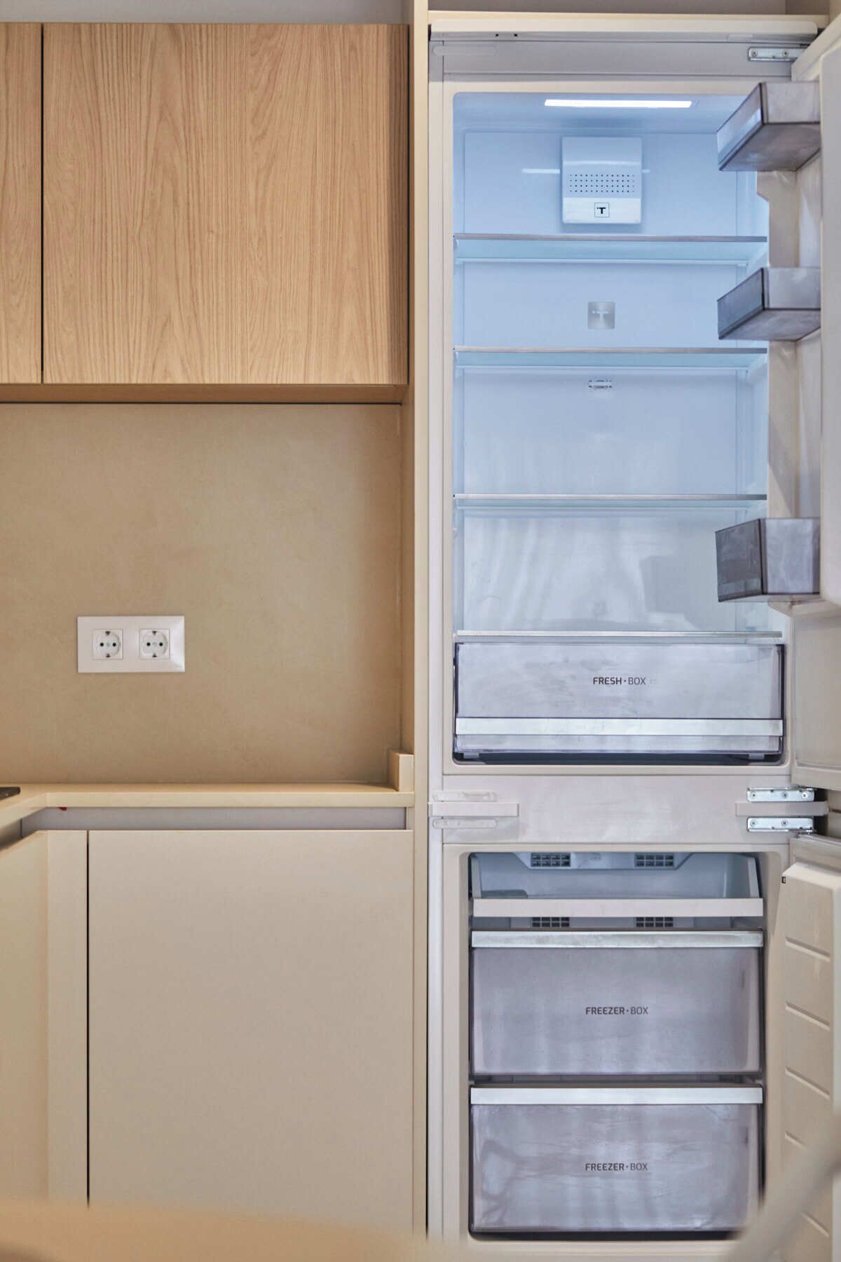 Een moderne keuken met een inbouwkoelkast, vriezer en een verse lade.