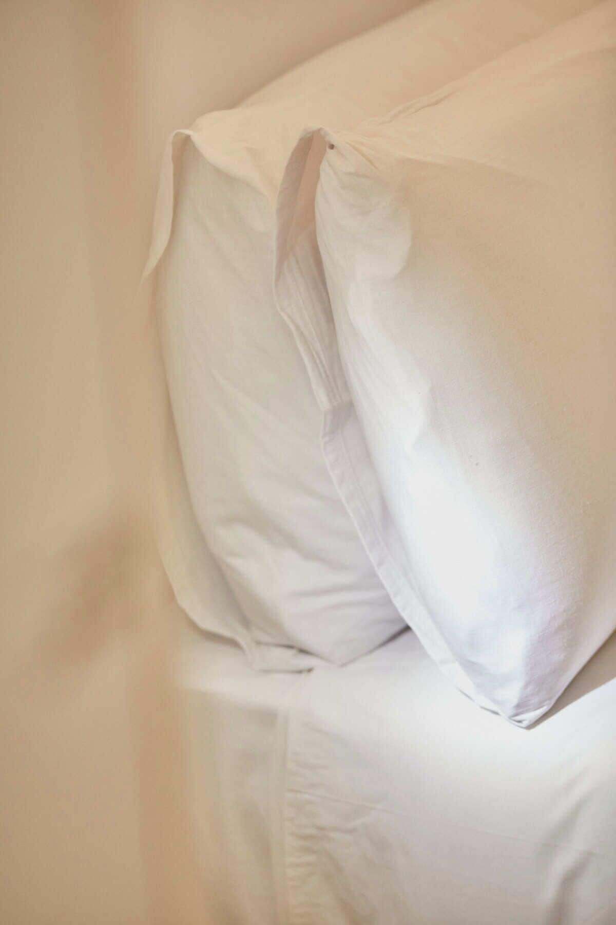 Primer plano de una cama blanca con una almohada cuidadosamente tendida.