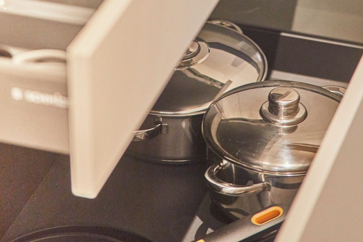 A kitchen drawer with multiple compartments, including a section for utensils and another for cookware.