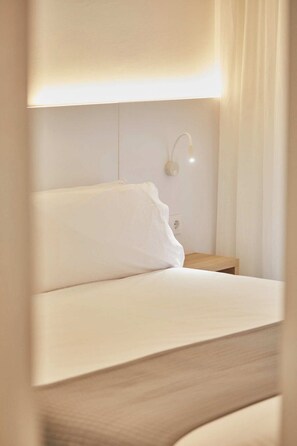 A hotel room with a bed, a nightstand, and a wall-mounted lamp. - Silken Atlantis Playa – Holiday Homes (Las Palmas de Gran Canaria)