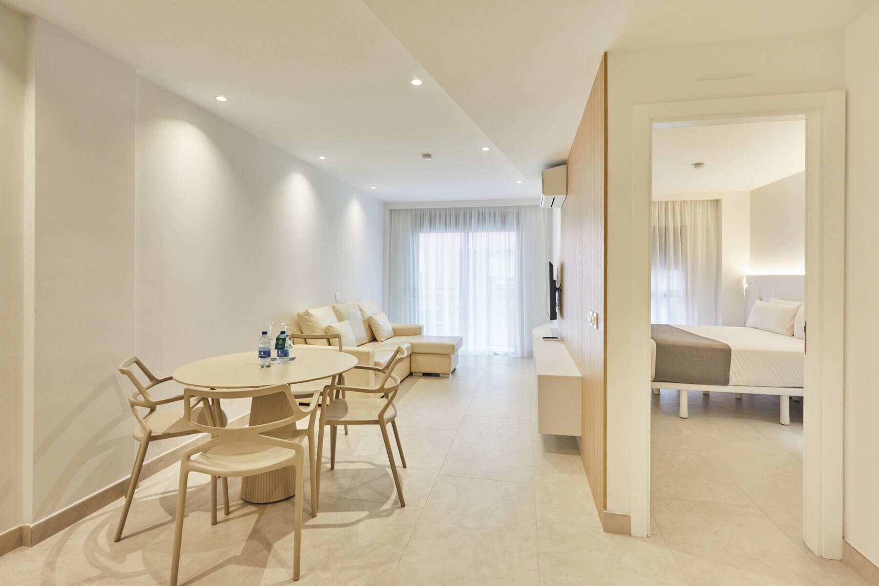 Een moderne hotelkamer met een eethoek, een bank en een bed.