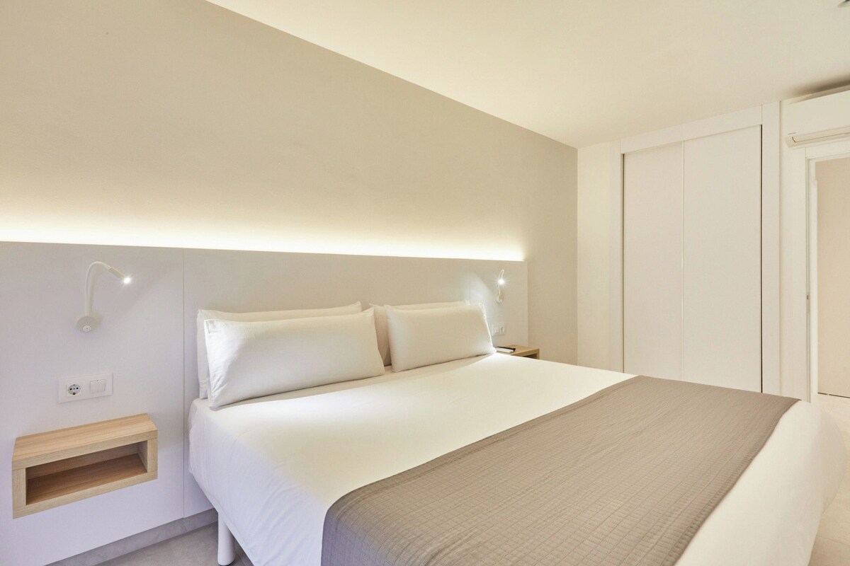 A hotel room with a bed, bedside table, and a wardrobe.