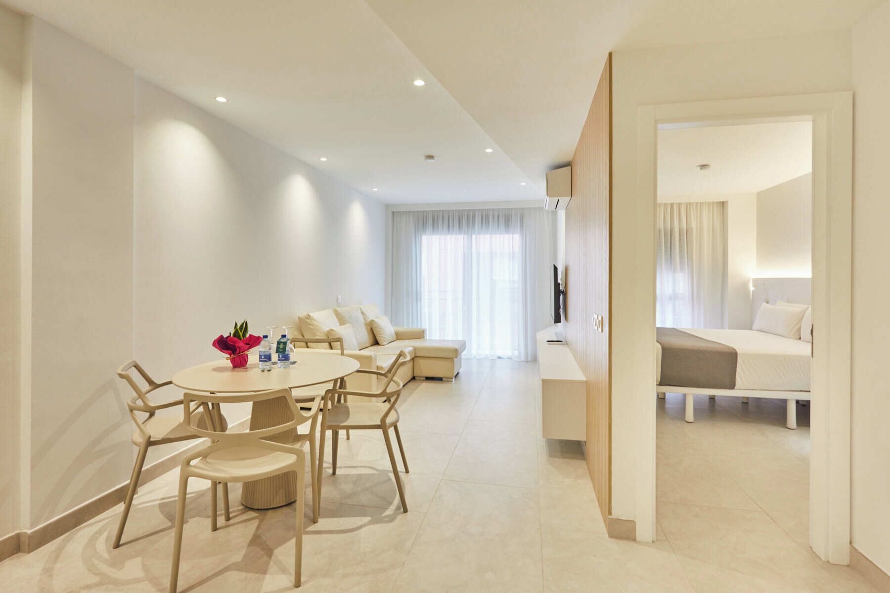 A modern hotel room with a dining area, a sofa, and a bed.