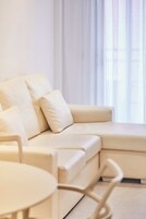 Un soggiorno moderno con un divano angolare beige, un tavolino rotondo e un'area pranzo con una sedia.