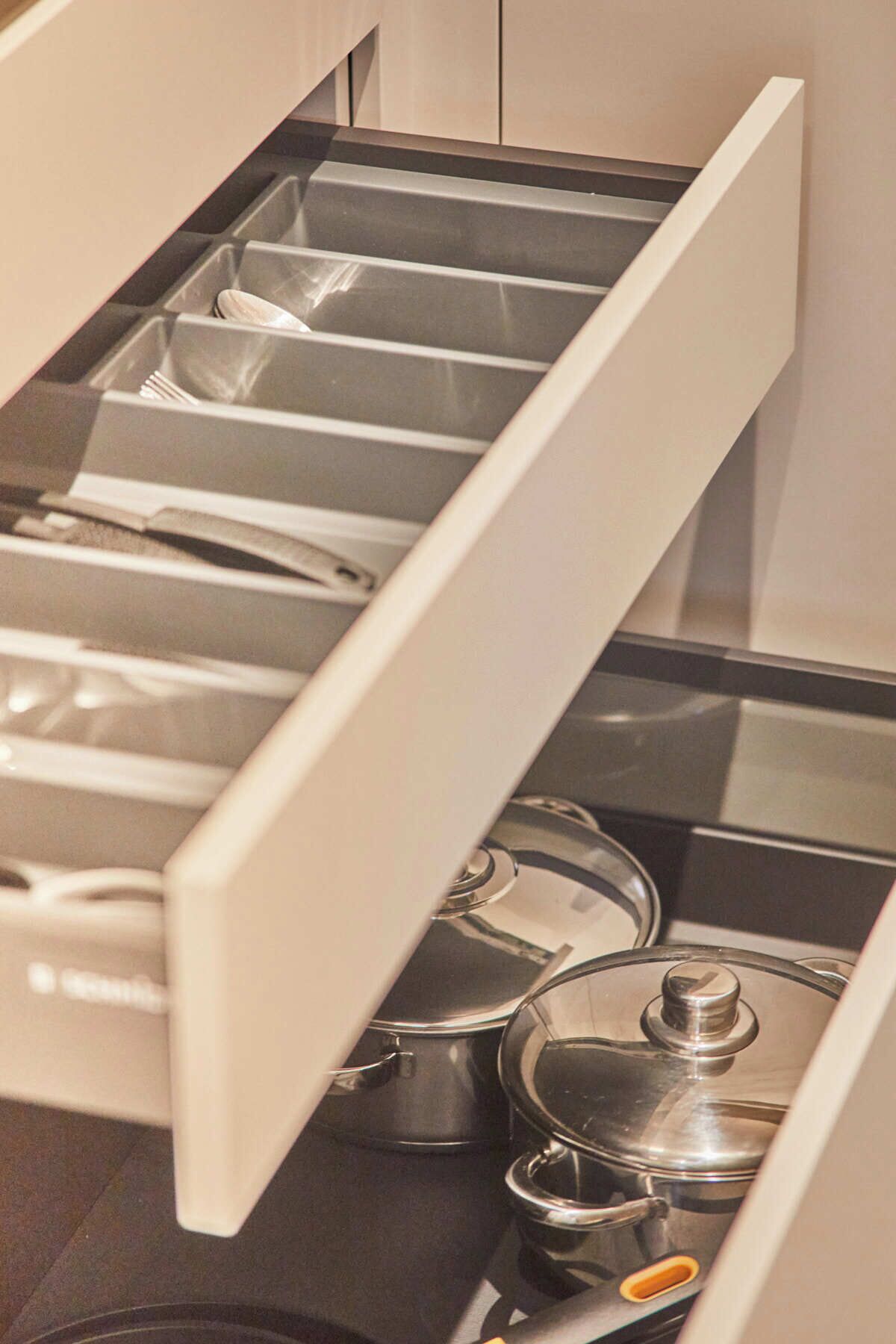 Un cajón de cocina con varios compartimentos, incluyendo un espacio para utensilios y otro para utensilios de cocina.