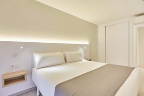 A hotel room with a bed, bedside table, and a wardrobe.