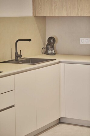 A kitchen with a modern design, featuring a sink, a coffee machine, and light-colored cabinets. - Silken Atlantis Playa – Holiday Homes (Las Palmas de Gran Canaria)