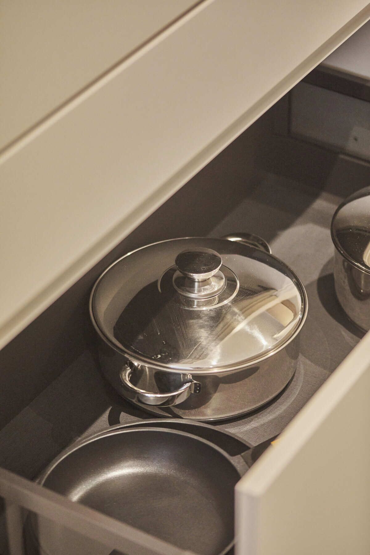 A kitchen drawer with stainless steel pots and pans.