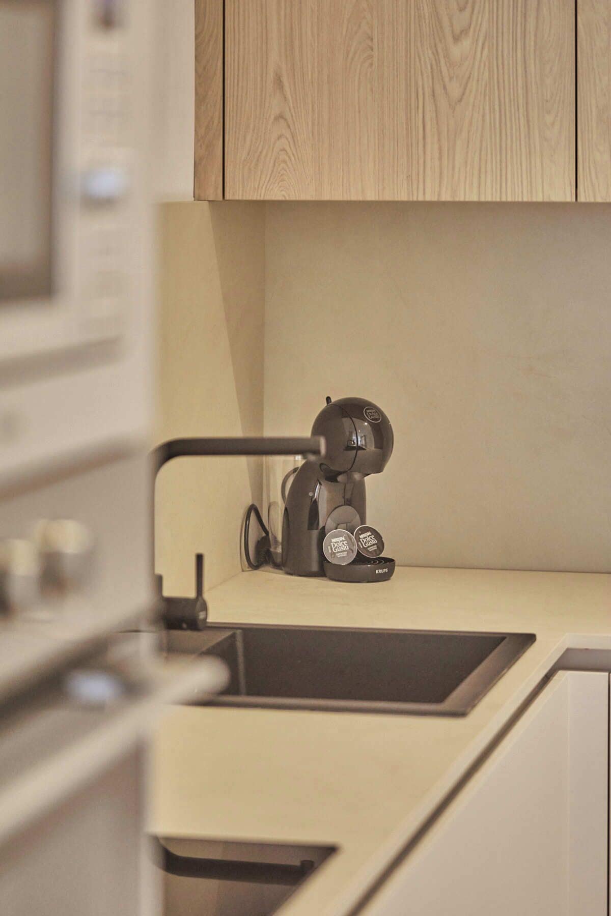 A modern kitchen with a built-in coffee machine and a single cup holder.