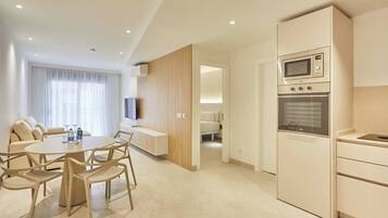 Una habitación de hotel moderna con zona de comedor, kitchenette y cama.