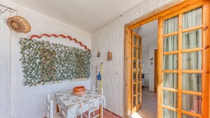 A dining area with a table and chairs, a decorative wall, and a wooden door. - Room in Guest Room - Studio Monolocale Margherita With Sea View, Balcony & Wi-fi (Salve)