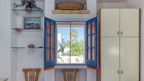 A room with a window, two chairs, a wardrobe, and a shelf with a painting. - Room in Guest Room - Studio Monolocale Margherita With Sea View, Balcony & Wi-fi (Salve)