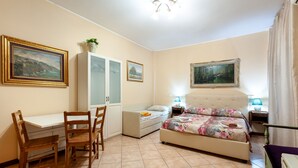 A bedroom with a bed, a desk, and a chair. There are two paintings on the walls. - Studio Near San Pietro (Rome)