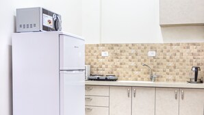 Eine moderne Küche mit einem weißen Kühlschrank, einer gefliesten Spritzschutzwand und hellen Holzschränken.