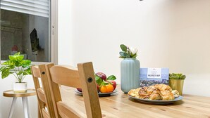 Ein Holztisch mit einer Platte Gebäck, einer Blumenvase und einer Karte darauf.