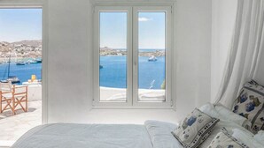 A bedroom with a large window overlooking a coastal town and the sea. - Villa Panoramic Mykonos Near Nammos (Mykonos)