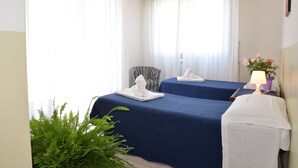 A hotel room with two beds, a chair, a table with a lamp, and a potted plant. - Room-two-room Apartment (Arezzo)