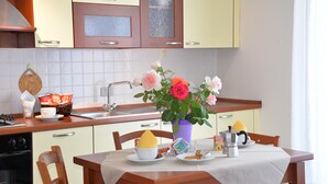 A kitchen with a dining table, chairs, a vase with flowers, and a coffee maker. - Room-two-room Apartment (Arezzo)