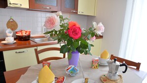 A dining table with a coffee pot, a knife, a plate with toast, a bowl of soup, and a vase with flowers. - Room-two-room Apartment (Arezzo)