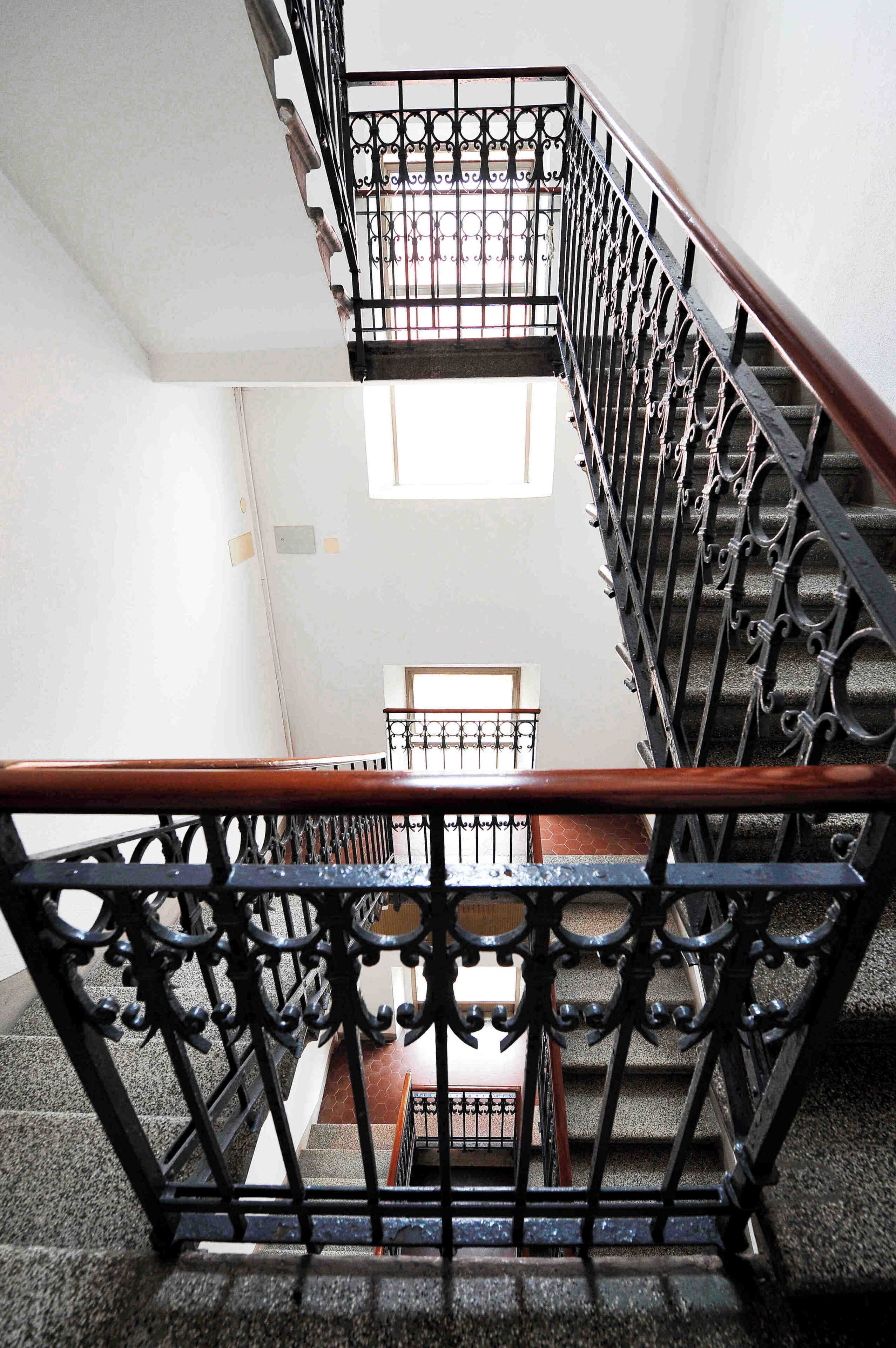 A staircase with ornate black metal railings and wooden handrails.