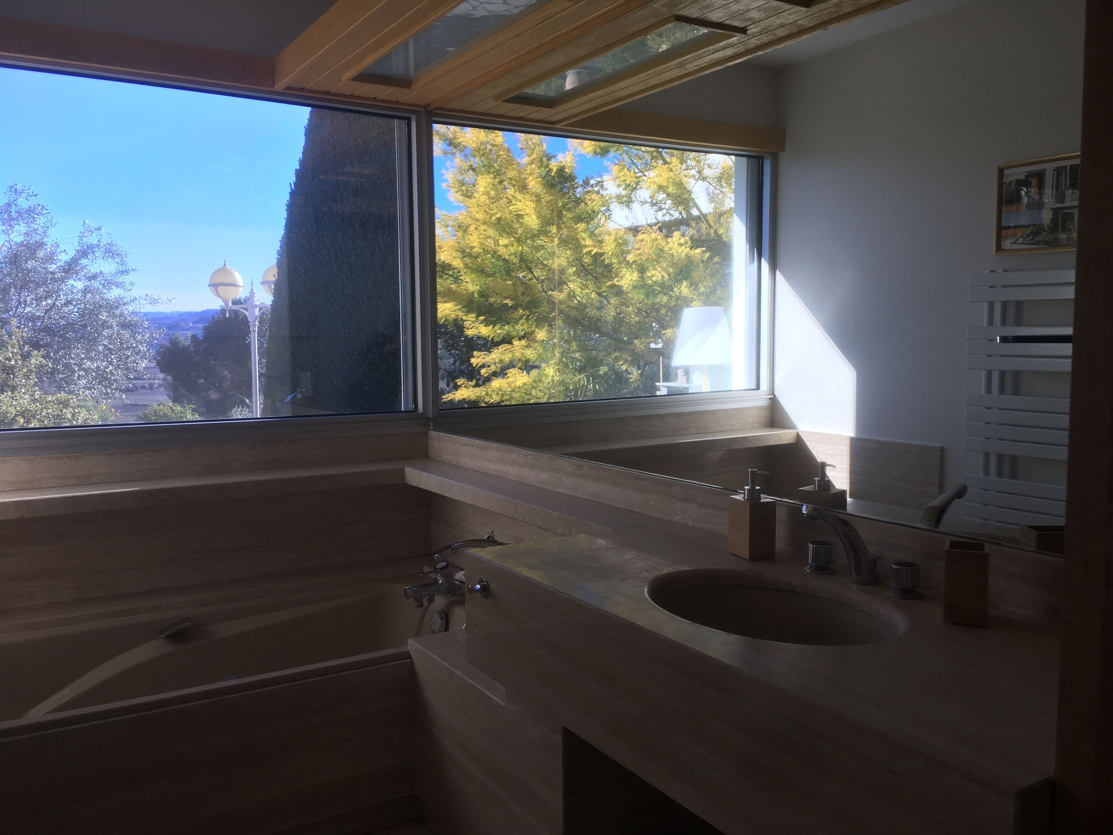 Une salle de bain moderne avec une grande fenêtre, un meuble-lavabo en bois et un évier.