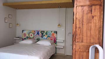 Una camera da letto con un letto, un armadio in legno, una testiera colorata e uno scaffale bianco.