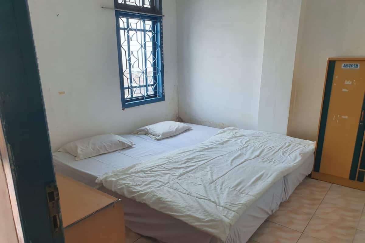 A single-bed room with a window, a door, and a small table.