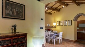 Un coin repas avec une table dressée pour quatre personnes, un buffet en bois, un vase décoratif et un tableau accroché au mur.