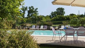 Un espace aménagé au bord de la piscine, avec des chaises longues et un grand parasol.